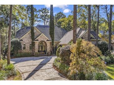 Elegant brick home with a circular driveway and meticulously landscaped front yard, creating a welcoming entrance at 89 Gleneagle Ln., Pawleys Island, SC 29585
