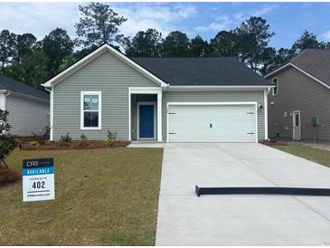 Charming one-story home featuring light green siding, a blue front door, and an attached two-car garage at 389 Sun Colony Blvd., Longs, SC 29568