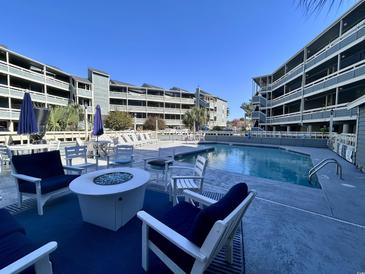 Resort-style condo pool with fire pit and lounge chairs offer a relaxing vacation experience at 1101 Possum Trot Rd. # B302, North Myrtle Beach, SC 29582