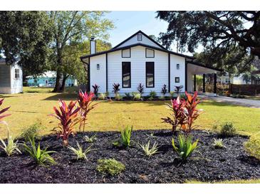 Charming home with a white exterior, black trim, well-maintained lawn, and lovely landscaping at 37 Geney Ln., Pawleys Island, SC 29585