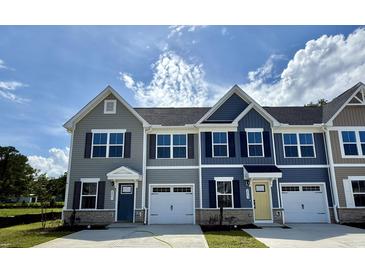 Attractive townhomes with attached garages, various siding colors and stone accents under a partly cloudy sky at 2061 Nw Parow Ln Nw # F, Calabash, NC 28467