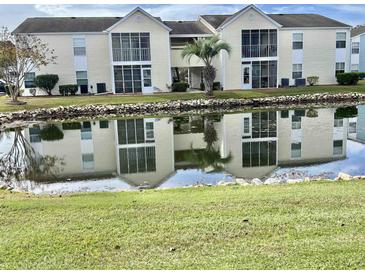 Scenic view of a two-story condo with a pond reflecting the facade and palm tree at 8830 Chandler Dr. # G, Surfside Beach, SC 29575