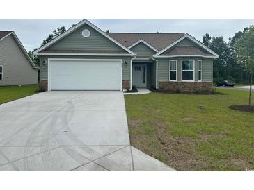 Charming single-story home with green siding, stone accents, a white garage door, and a well-maintained front lawn at 910 Padgett Lane, Conway, SC 29526