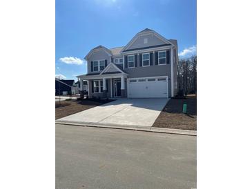 Charming two-story home boasts gray siding, black shutters, covered entryway, and a spacious two-car garage at 1999 Woodrush Loop, Little River, SC 29566