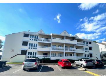 Front view of a three-story building with several apartment units and parking in front at 1100 Possum Trot Rd. # F-215, North Myrtle Beach, SC 29582