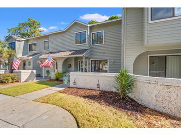 Inviting exterior of a light gray townhouse with American flags and well-manicured landscaping at 23 Shadow Moss Pl. # 23, North Myrtle Beach, SC 29582