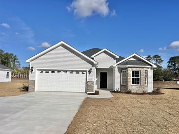 Charming single Gathering home featuring a two-car garage and vinyl siding, complemented by well-manicured landscaping at 4963 Old Highway 90, Conway, SC 29526