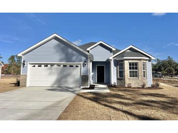 Charming one-story home featuring light blue siding, attached garage, and well-maintained landscaping under a clear blue sky at 4971 Old Highway 90, Conway, SC 29526