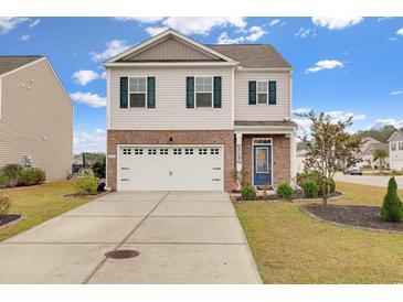 Charming two-story home featuring a blue front door, a brick-accented facade, and a spacious two-car garage at 568 Affinity Dr., Myrtle Beach, SC 29588
