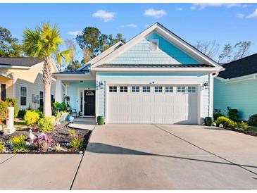 Charming, light blue home featuring an attached garage and a well-manicured front yard with lush tropical landscaping at 1604 Carsens Ferry Dr., Conway, SC 29526