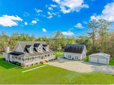 Stunning home boasts a sprawling lawn, charming front porch, additional garage, and separate building at 865 River Rd., Tabor City, NC 28463