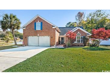 Charming brick home featuring an attached two-car garage, a well-manicured lawn, and an adjacent pond at 305 Duel Ct., Myrtle Beach, SC 29588