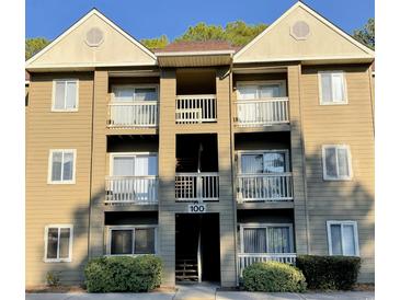 Three-story condo building featuring exterior balconies with white railings and a well-kept landscape at 100 G Myrtle Greens Dr. # G, Conway, SC 29526