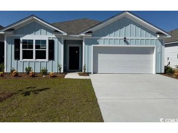Charming single-story home featuring a blue exterior, attached garage, and well-manicured lawn at 556 Duvall St., Longs, SC 29568