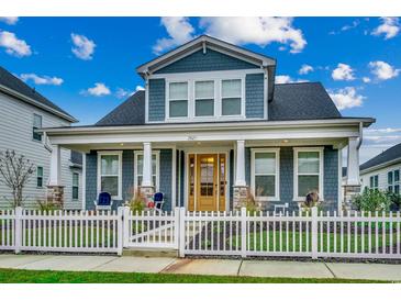 Charming two-story home with a covered porch, white picket fence and nicely landscaped front yard at 2023 Singing Palm Loop, Little River, SC 29566