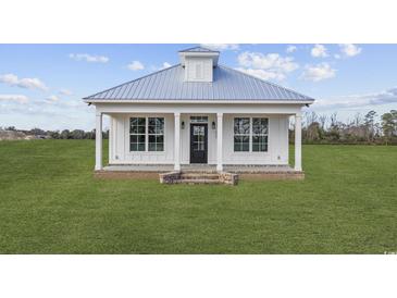 White cottage with metal roof, front porch, and brick steps at 3368 Gurley Rd., Loris, SC 29569