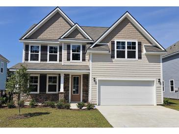 Inviting two-story home featuring a two-car garage, manicured lawn, and charming stone accents around the entryway at 550 Haven View Way, Murrells Inlet, SC 29576