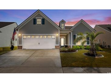 Charming single-Gathering home boasts an attached two-car garage, manicured lawn, and inviting curb appeal at 6550 Anterselva Dr., Myrtle Beach, SC 29572