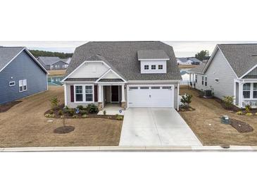 Beige two-story house with a gray roof, white garage door, and landscaping at 1262 Witch Hazel Way, Longs, SC 29568