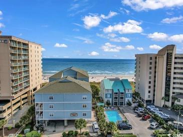 Beautiful exterior view of the condo buildings, parking lot, and community pool near a beach at 507 S Ocean Blvd. # 201, North Myrtle Beach, SC 29582
