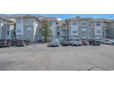 Exterior view of a condo building with parking lot and landscaping at 70 Addison Cottage Way # 319, Murrells Inlet, SC 29576