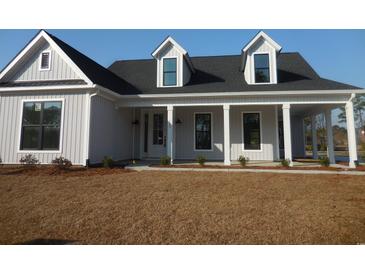 Charming single-Gathering home featuring a welcoming front porch with stylish columns and neutral-colored siding at 2220 Pettus Way, Surfside Beach, SC 29575