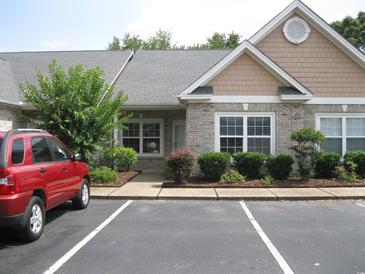 Charming single-story home with brick accents, manicured landscaping and a red SUV in the parking area at 4672 Lightkeepers Way # 50-E, Little River, SC 29566