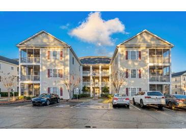 Inviting multi-story condo building showcases classic design with red shutters and ample parking space at 2060 Cross Gate Blvd. # 204, Surfside Beach, SC 29575