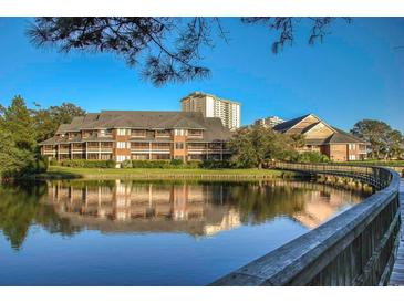 Beautiful view of an exterior building with waterfront access and a wooden bridge over the lake at 410 Melrose Pl. # 219, Myrtle Beach, SC 29572