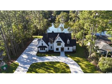 Aerial view of a two-story house with a large driveway and a pond in the background at 101 Green Lake Dr., Myrtle Beach, SC 29572