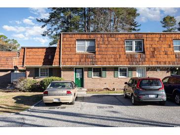 Charming brick townhouse featuring unique wood roofing, green shutters and door, and ample parking space at 1025 Carolina Rd. # Y-1, Conway, SC 29526