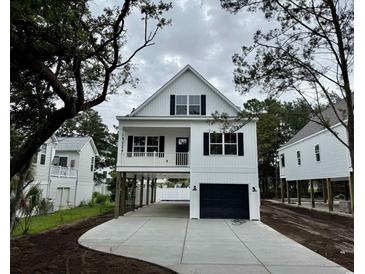 Charming two-story coastal home with black shutters, a covered porch and a driveway leading to a garage at 1718 26Th Ave. N, North Myrtle Beach, SC 29582