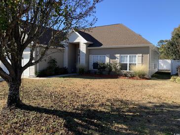 Beige house with brown roof, landscaping, and a large tree in front at 231 Jessica Lakes Dr., Conway, SC 29526