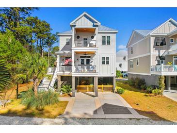 Two-story home with white siding, large windows, and a two-car garage at 34 Lazy Hammock Trail, Pawleys Island, SC 29585