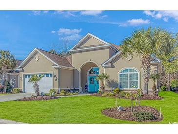 Tan two-story house with teal door, two-car garage, and landscaped yard at 5504 Via Verde Dr., North Myrtle Beach, SC 29582