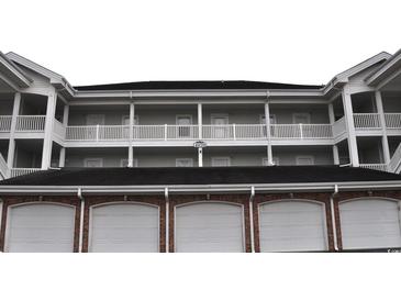 Exterior view of multi-story condo building with brick facade and white railings, showcasing a well-maintained property at 4870 Dahlia Ct. # 303, Myrtle Beach, SC 29577