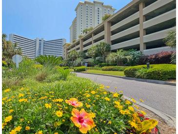 Oceanfront property with lush landscaping and parking garage in background at 9994 Beach Club Dr. # 506, Myrtle Beach, SC 29572