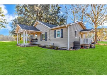 Beige house with a large green lawn and a porch at 3703 Green Sea Rd., Green Sea, SC 29545
