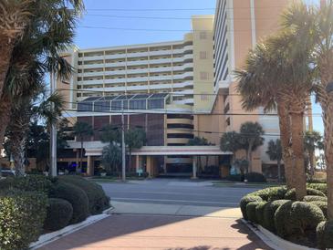 View of the Caravelle Resort's exterior, featuring palm trees and convenient covered parking at 6900 N Ocean Blvd. # 614, Myrtle Beach, SC 29572