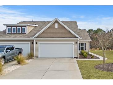 Tan colored exterior of house with two car garage and landscaped yard at 7015 River Bridge Ct, Myrtle Beach, SC 29579
