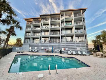 Building exterior with inviting pool area and palm trees at 1906 S Ocean Blvd. # 108A, Myrtle Beach, SC 29577