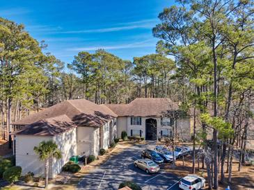 Aerial view of a condo building with surrounding trees and ample parking at 204 Pipers Glenn # 204, Myrtle Beach, SC 29575