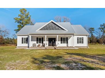 White farmhouse exterior with gray metal roof and front porch at 5300 Juniper Bay Rd., Conway, SC 29527