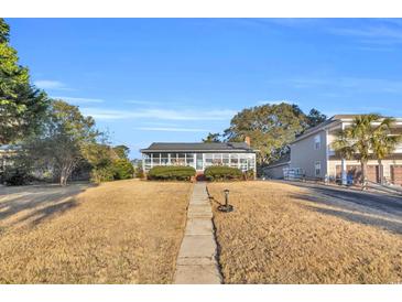 Brick ranch house with screened porch and landscaped yard at 5515 Porcher Dr., Myrtle Beach, SC 29577