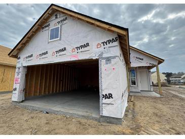 Exterior view of home under construction, showing garage, covered in Typar wrap, and front door at 1245 Lady Bird Way, North Myrtle Beach, SC 29582