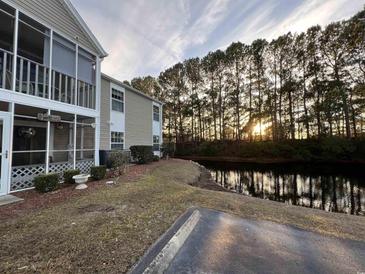 Exterior view of condo building showcasing a screened porch and a tranquil waterfront setting at 1925 Bent Grass Dr. # B, Surfside Beach, SC 29575