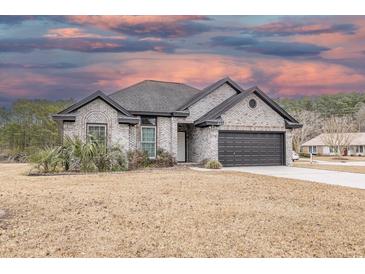 Brick home with dark gray garage door and landscaping at 603 Hatteras River Rd., Myrtle Beach, SC 29588