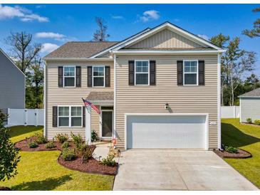 Two-story house with beige siding, white garage door, and landscaped front yard at 623 Meadowgrass Ct., Myrtle Beach, SC 29588