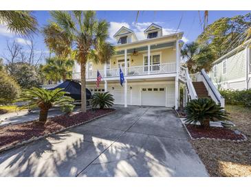 Two-story home with a large porch and two-car garage, surrounded by palm trees at 65 Harbourreef Dr., Pawleys Island, SC 29585