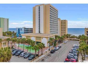 Lovely view of the property with a pool and palm trees in a parking area at 1205 S Ocean Blvd. # 50412, Myrtle Beach, SC 29577